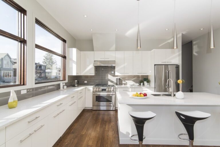 Modern kitchen with white cabinets, stainless steel appliances, and a bowl of fruit on the counter