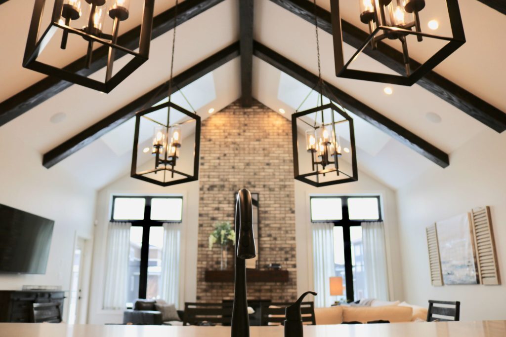 Spacious living room with vaulted ceiling, wood beams, and large statement chandeliers above the sitting area